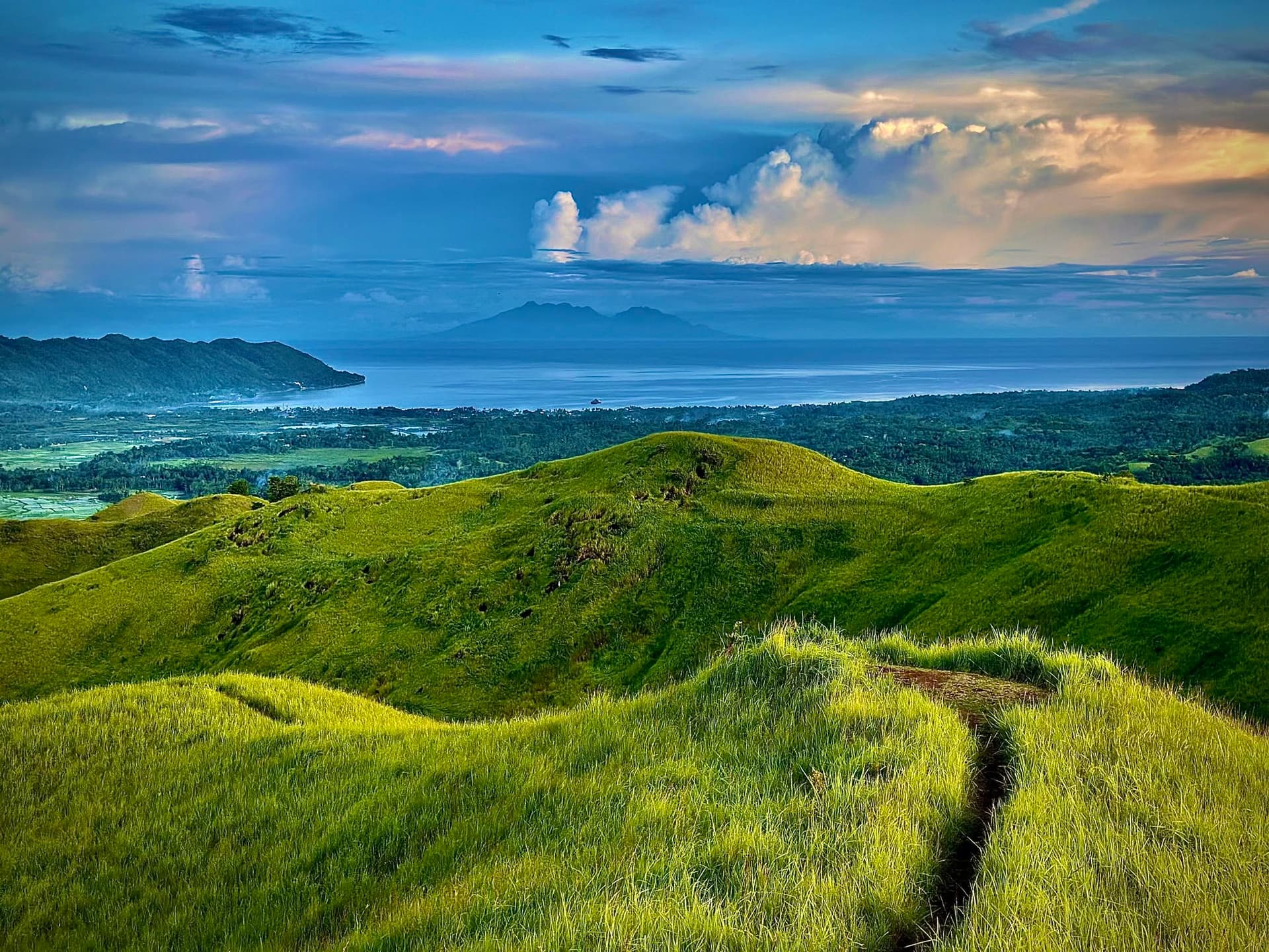 Expansive daytime vista of Candijay's undulating green ridges and rural landscape
